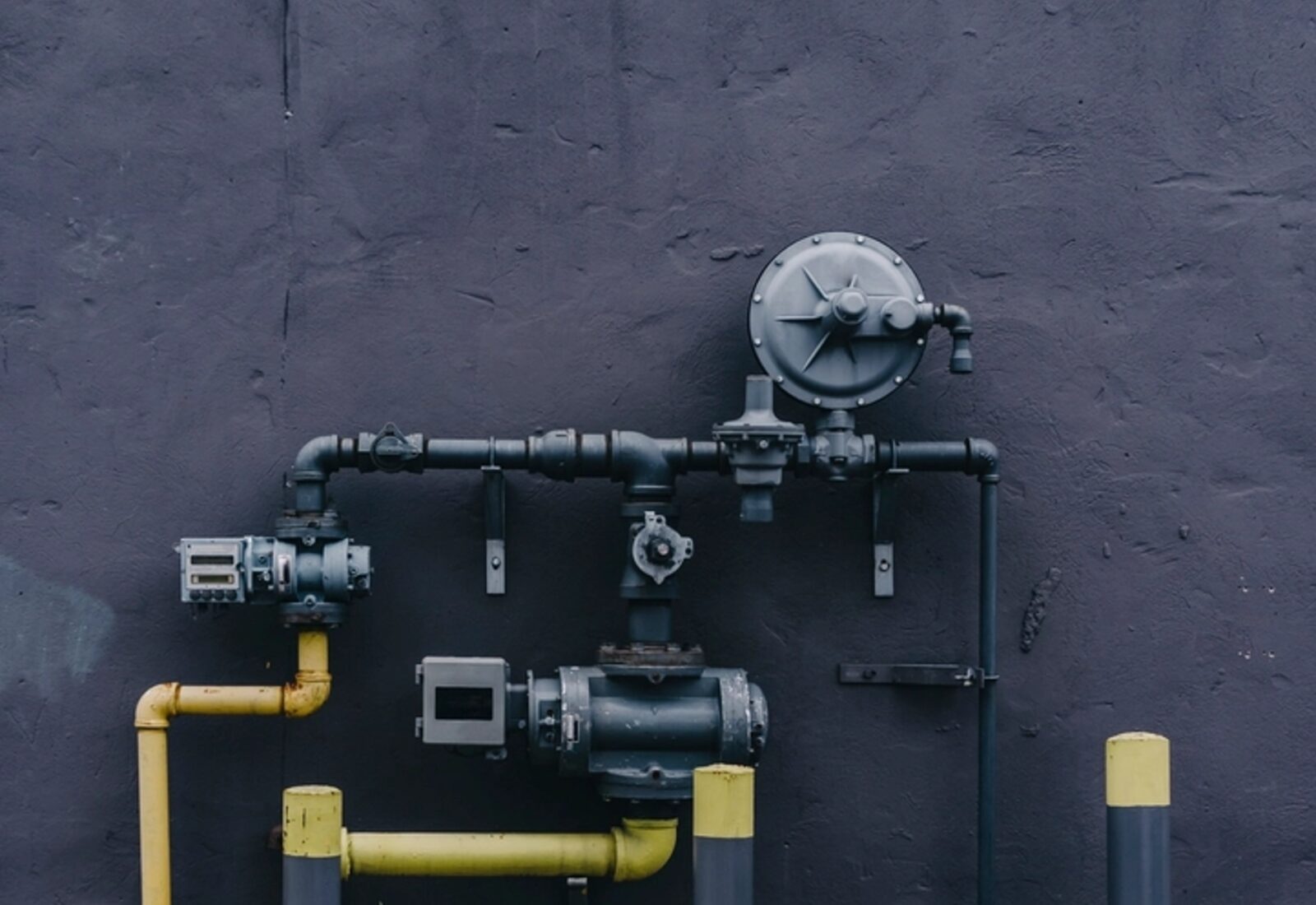 Service piping, valves and a meter on a mechanical wall